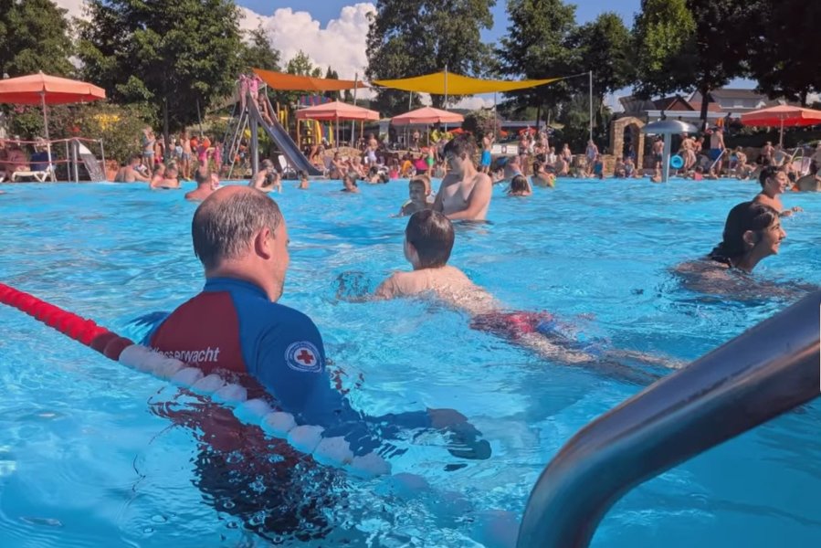 Mitglied der Wasserwacht mit schwimmenden Kindern im Ettenheimer Schwimmbad